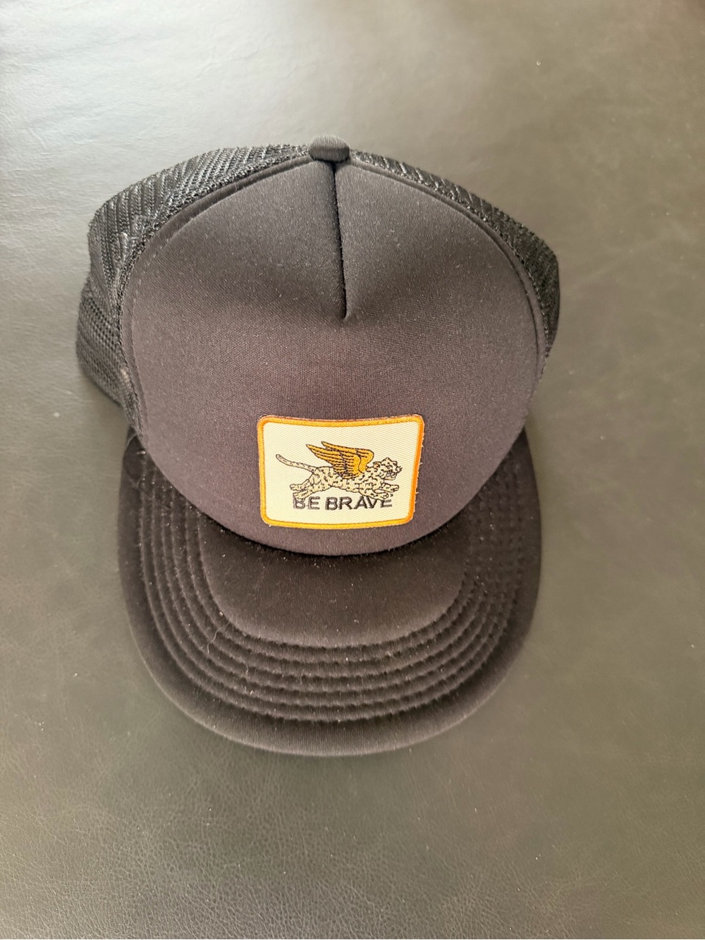Black Trucker Hat with 'Be Brave' Winged Lion Patch